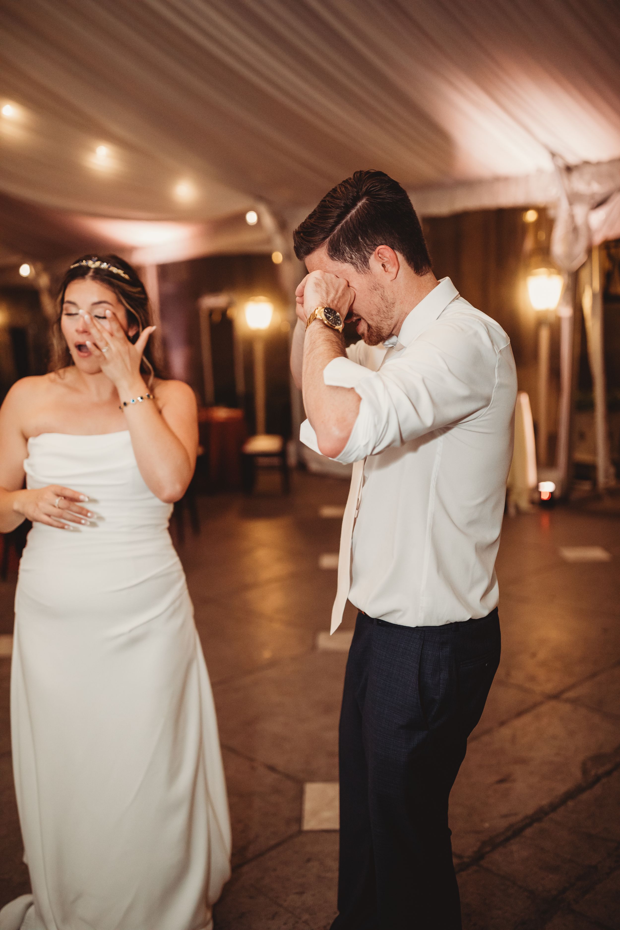 Bride and groom crying tears of joy during emotional first dance at elegant wedding reception venue.