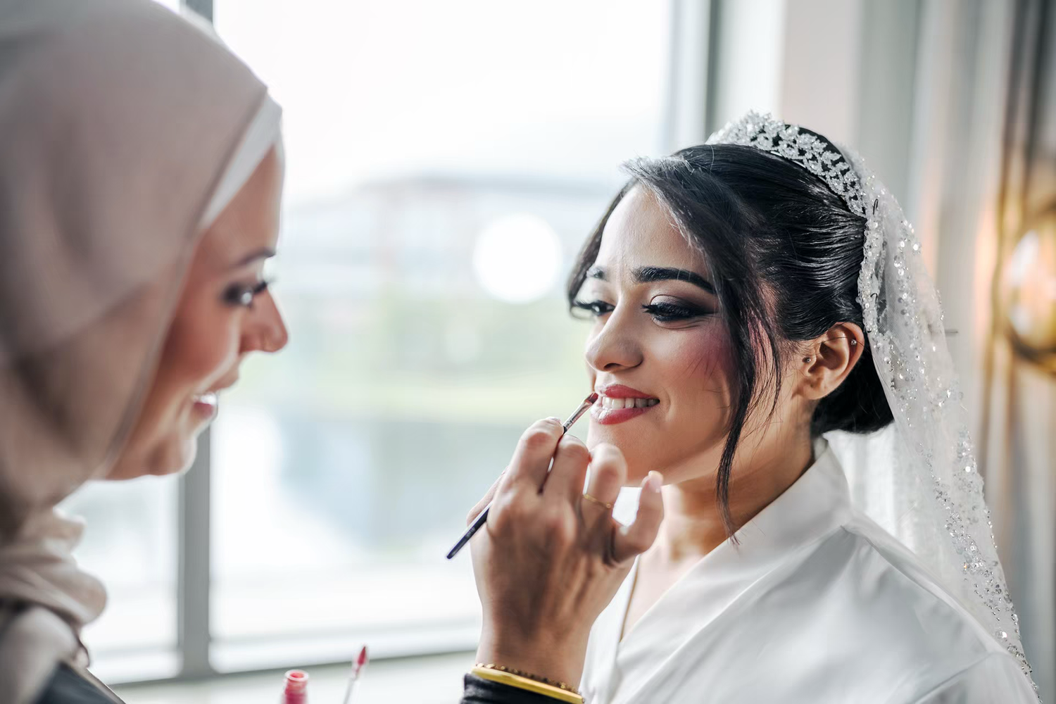 A makeup artist applies lipstick to a bride in renaissance  wedding venue.