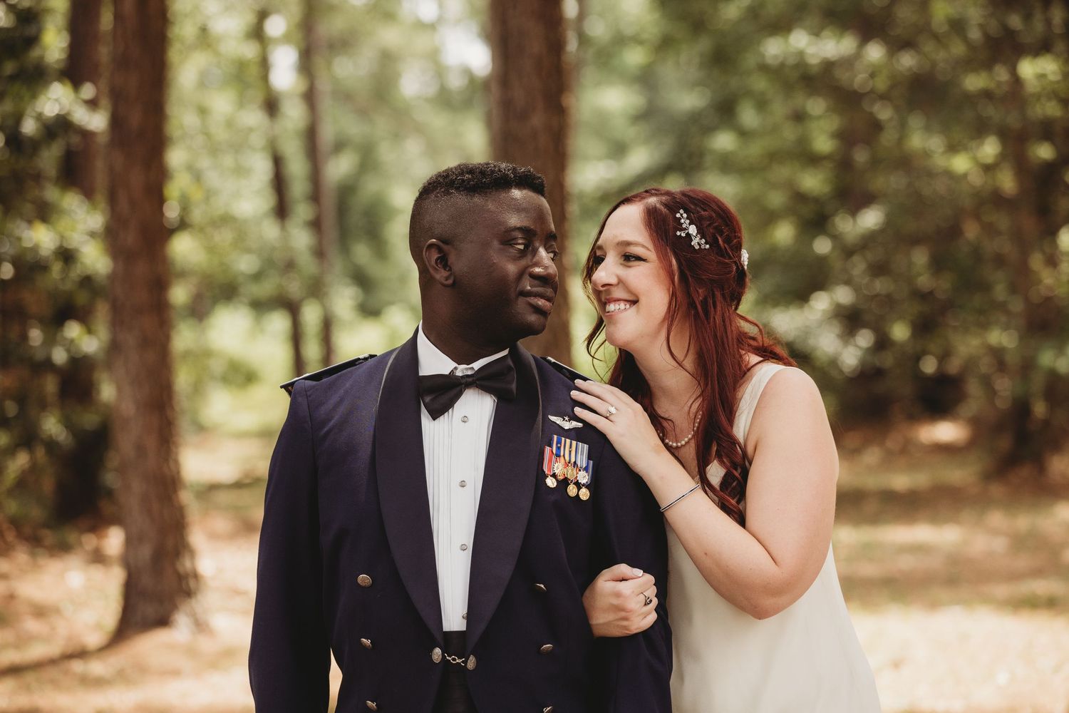 Bride and groom sharing a kiss between ornate wrought iron gates, bride holding white bouquet in elegant wedding attire.