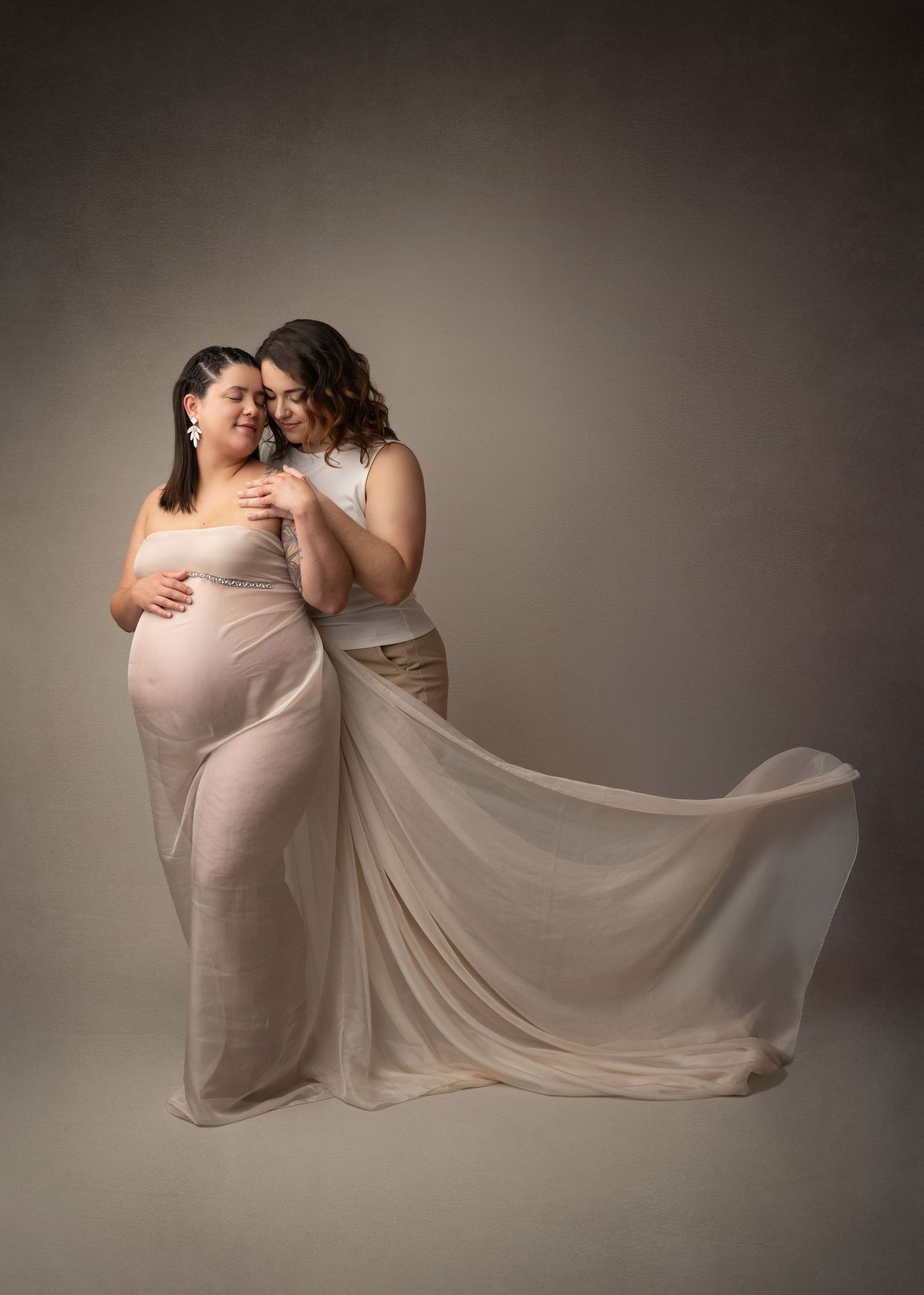 Two mothers to be embracing her pregnant belly in studio in linden, NJ