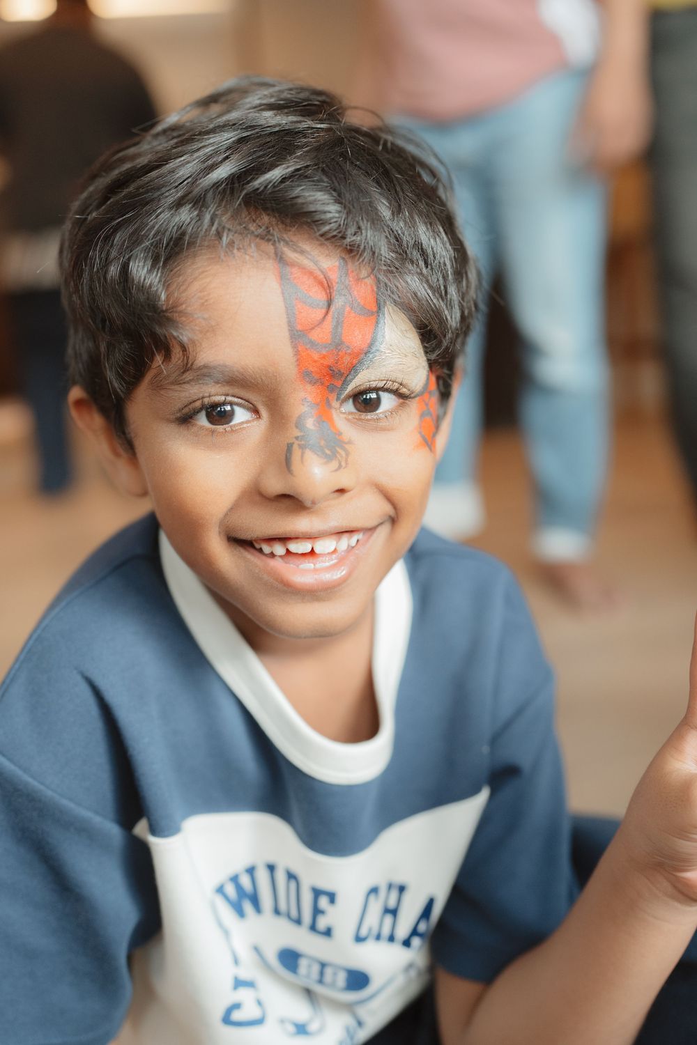 Smiling boy with colorful face paint design at a children's birthday party.
