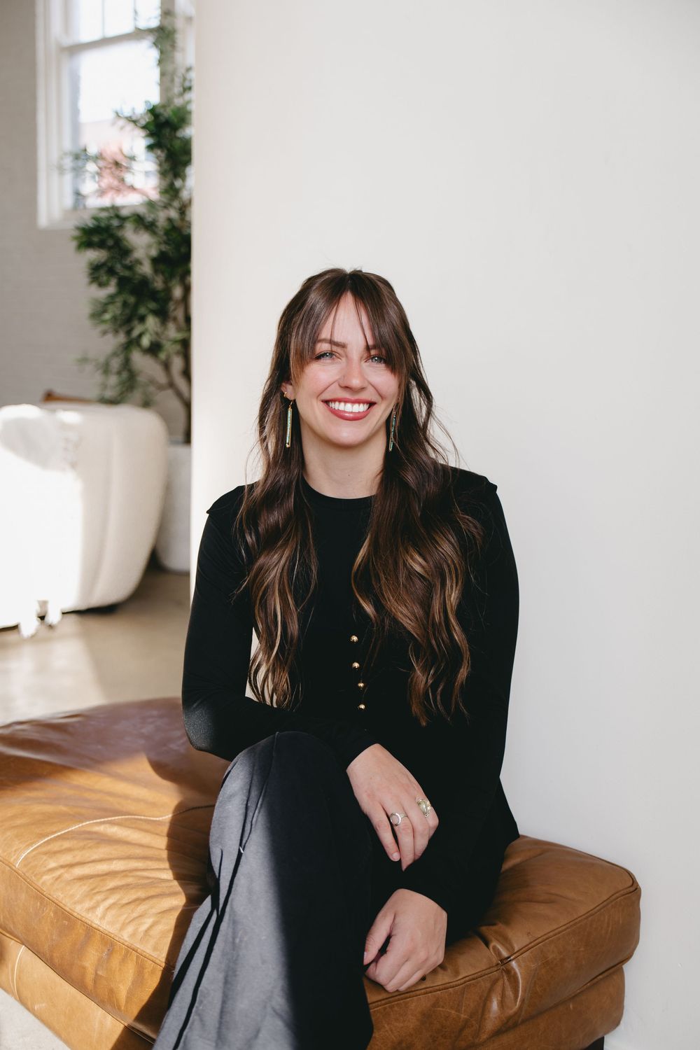 smiling woman sitting on a leather footrest
