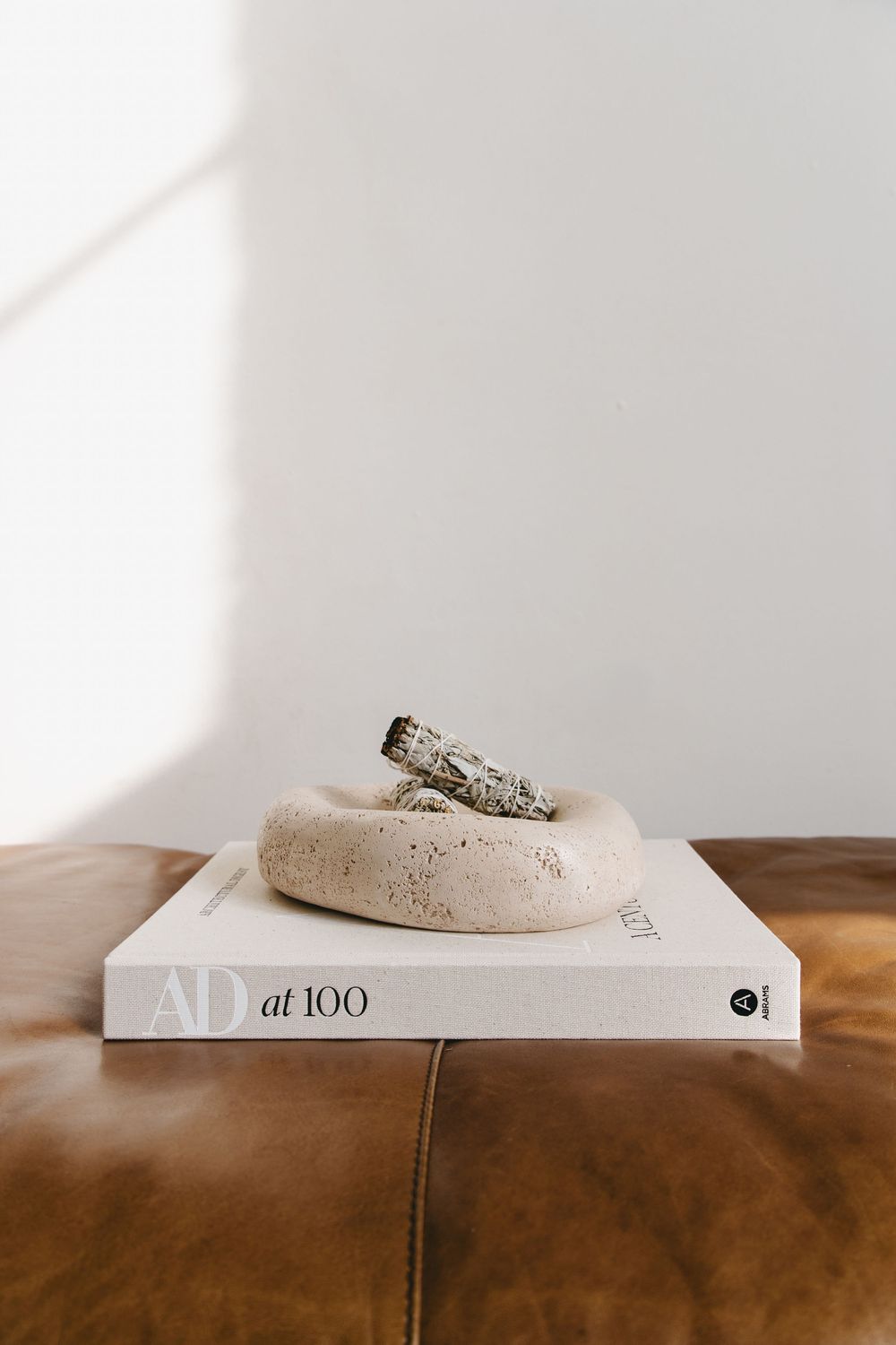 an interior design book staged with an ceramic tray containing sage