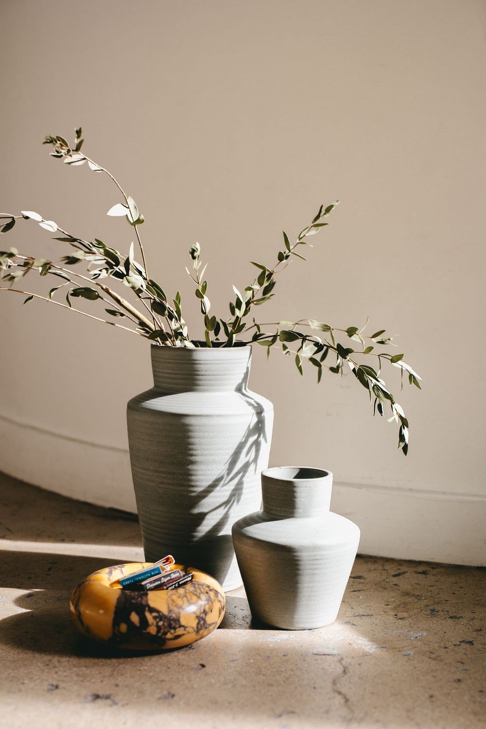 a vase with olive stems next to an ashtray