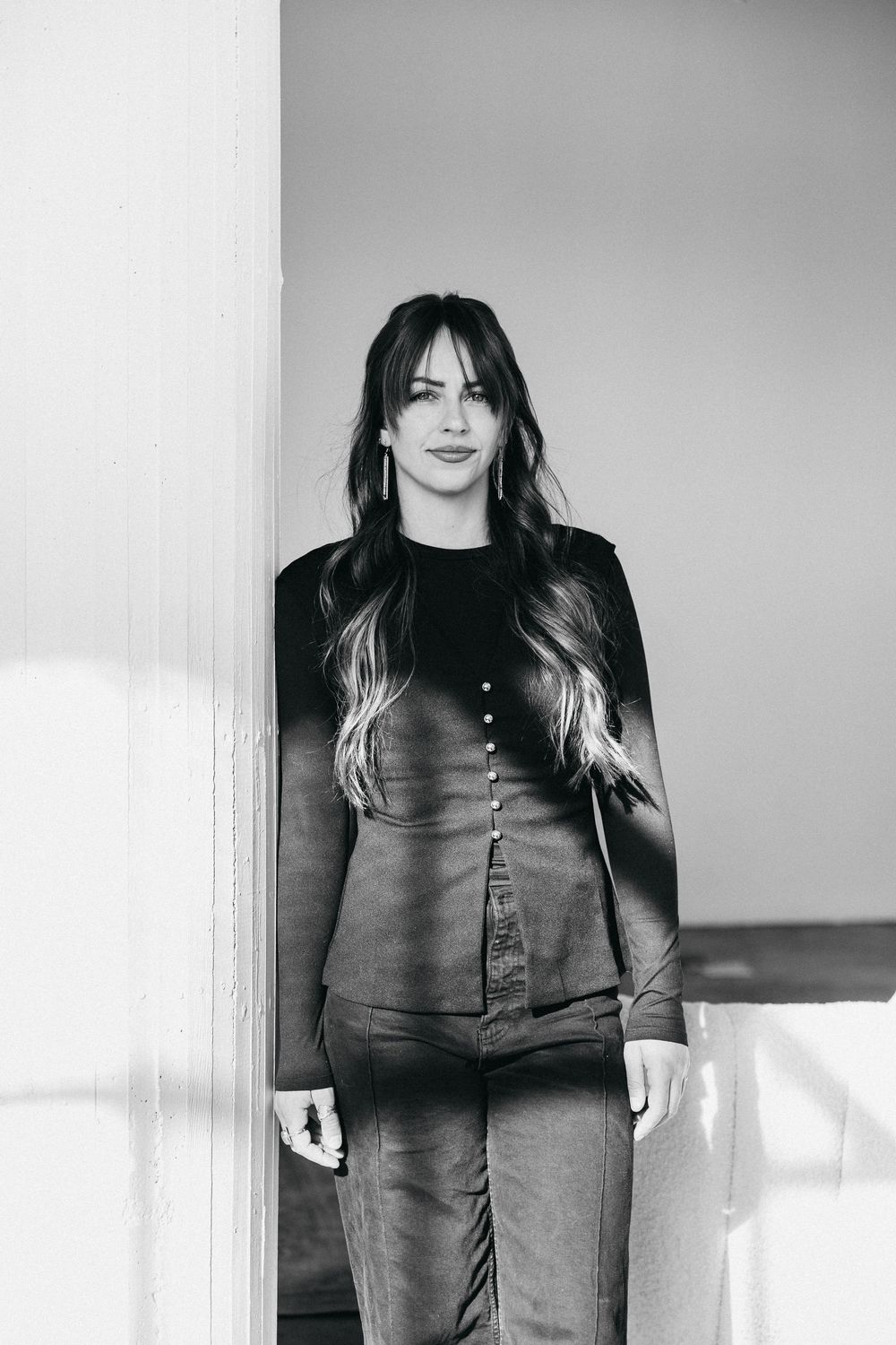 woman standing against a pillar wearing a buttoned top