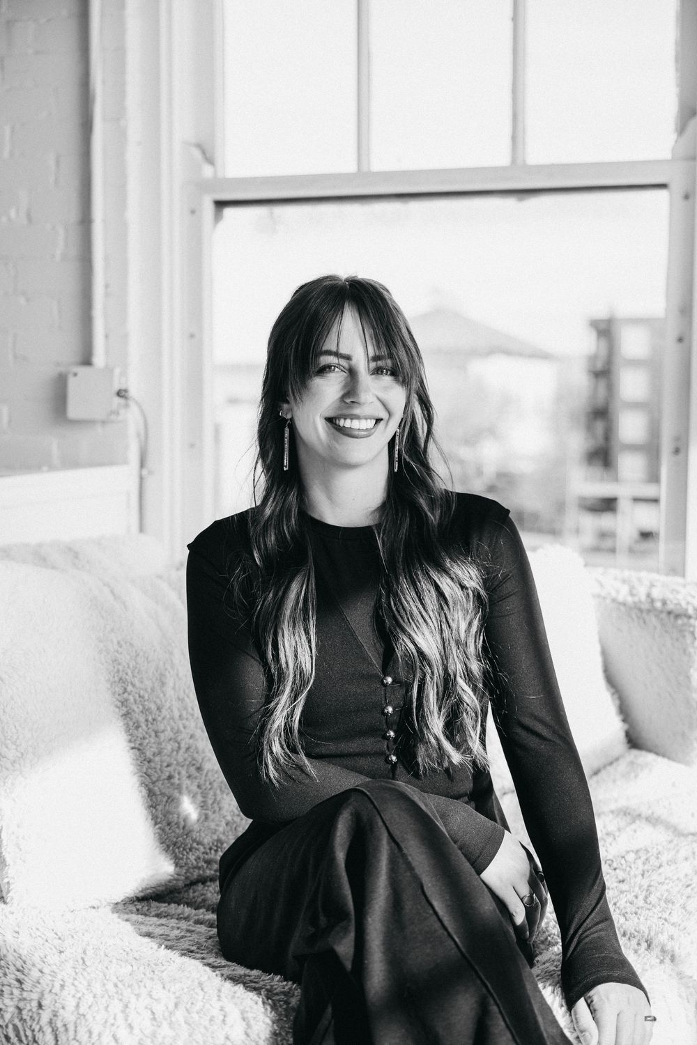 black and white image of a woman sitting on a round chair, smiling