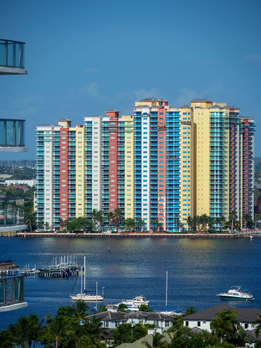 Colorful high-rise waterfront condominiums with marina and boats under a clear blue sky.