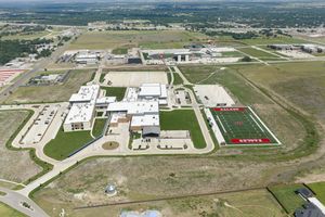 Aerial view of Salado ISD school campus with red turf football field and modern facilities in Texas.