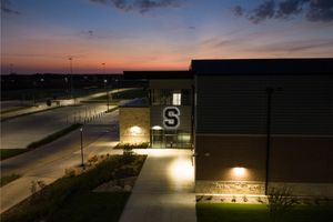 Exterior night view of Salado school building entrance illuminated at sunset with modern architecture.