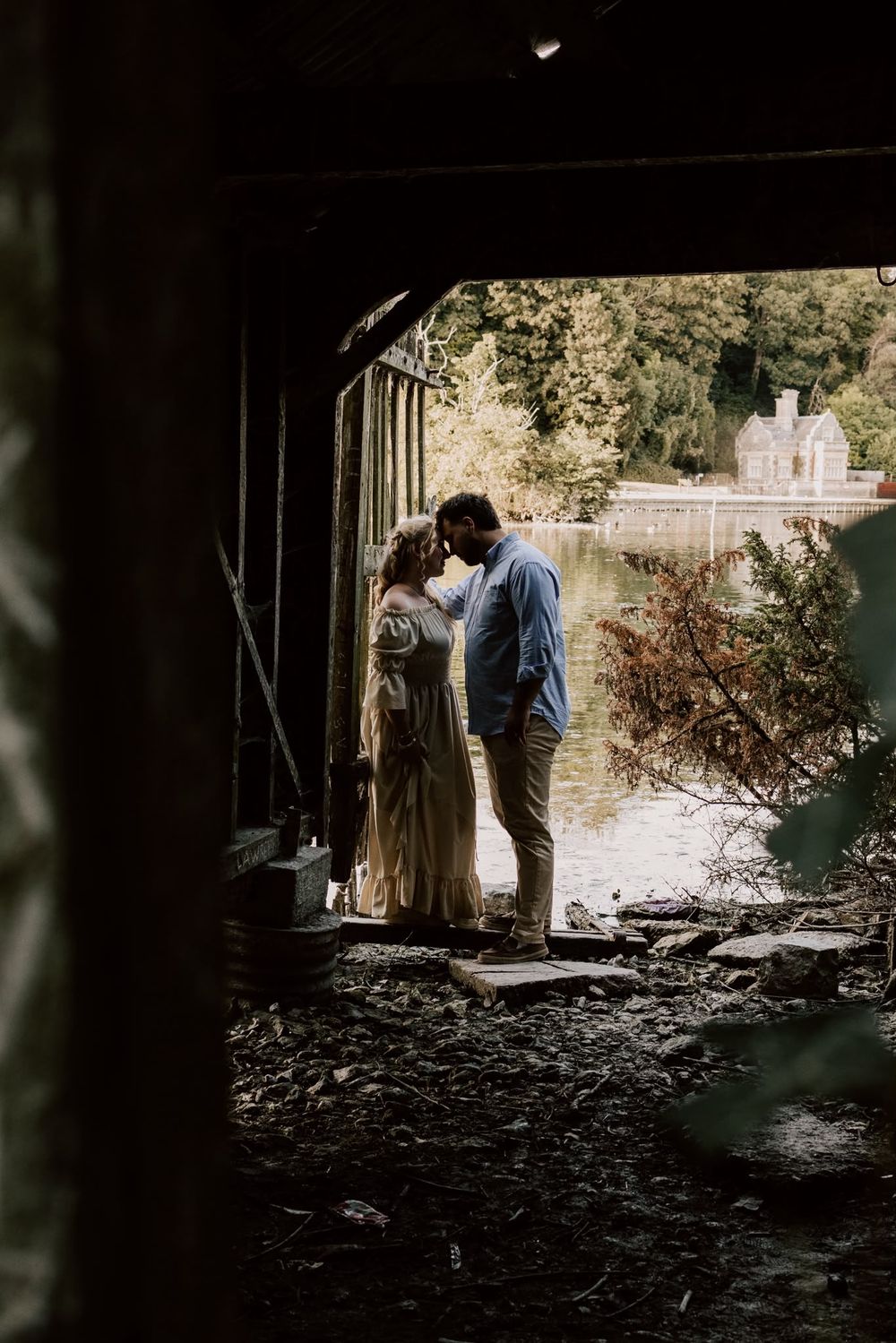 Couple standing together outdoors, framed through a dark doorway during an engagement shoot