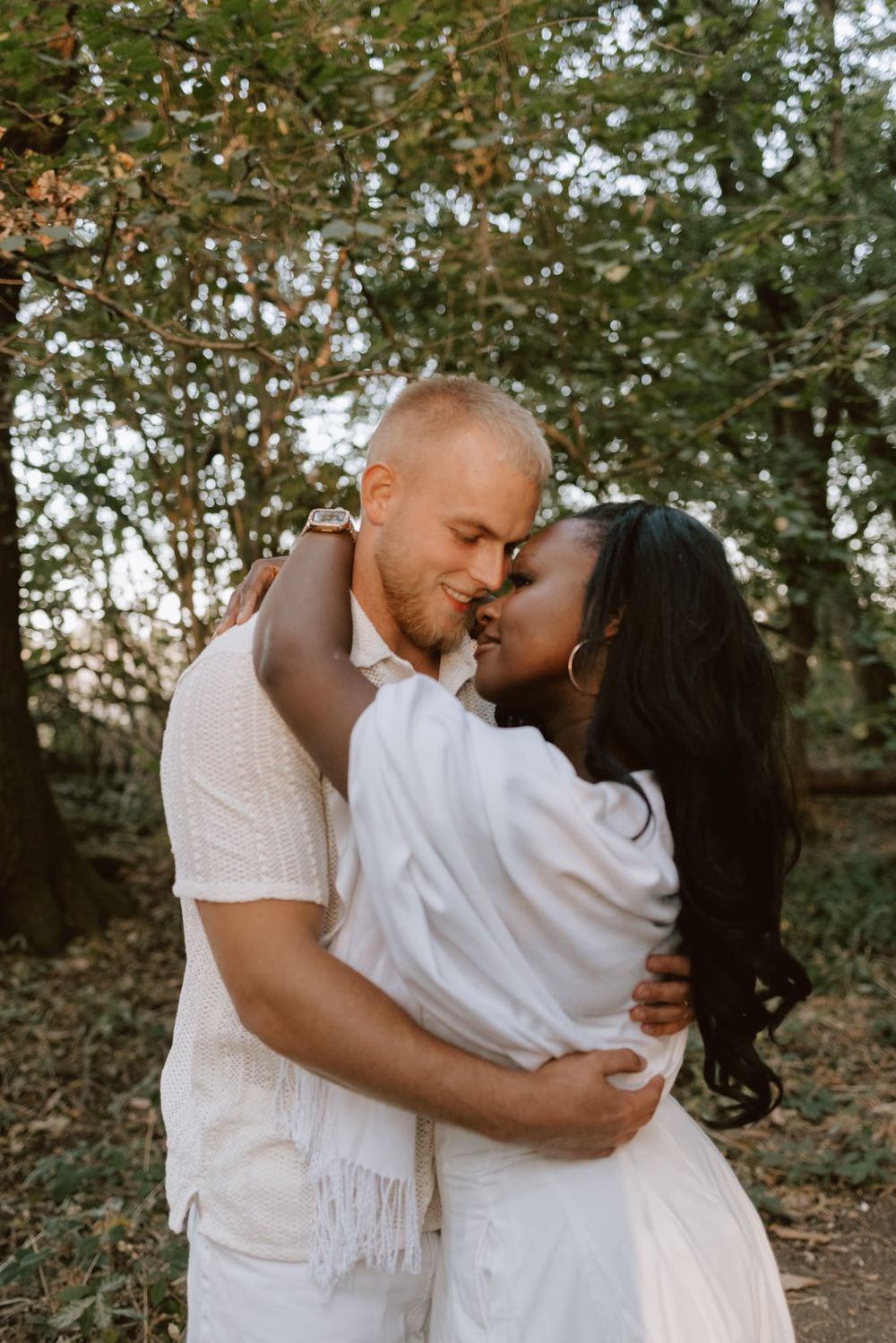 Candid photo of a couple embracing beneath the trees