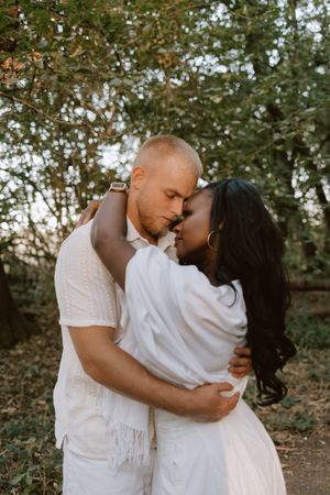 Candid photo of a couple embracing beneath the trees