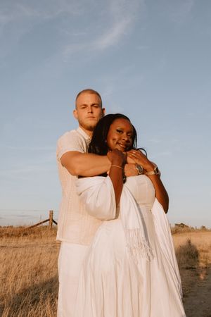 Couple laughing together in a field during a golden hour photoshoot