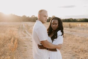 Couple embracing in a sunlit field during a relaxed engagement shoot