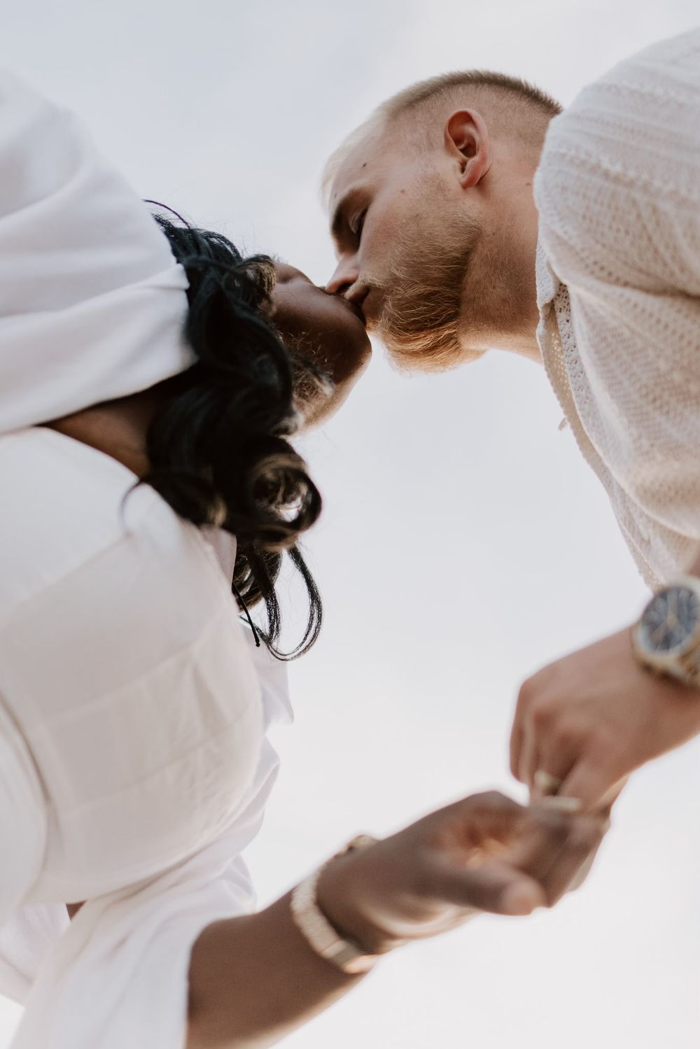 Low-angle photograph of a couple kissing and holding hands