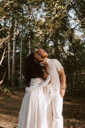 Romantic portrait of a couple looking up in a sunlit woodland setting