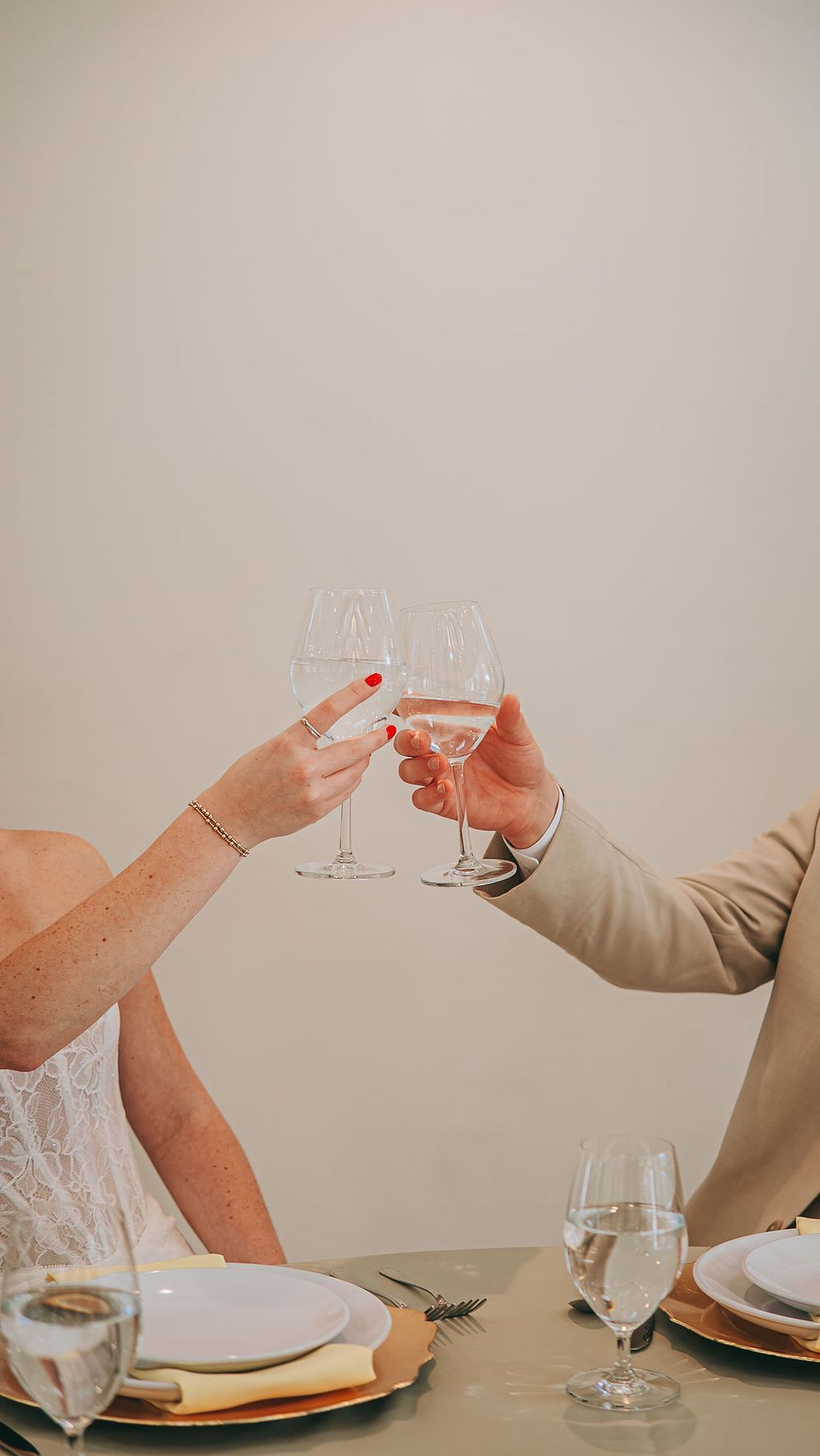 Bride and groom toasting with wine glasses at elegant wedding reception dinner table setting.
