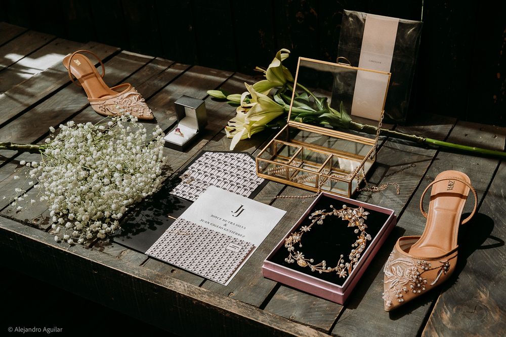 Elegant wedding flat lay with bridal accessories, flowers, jewelry, and heels on rustic wood.