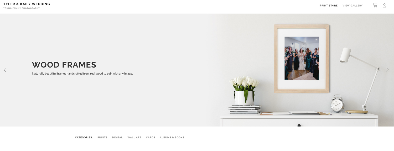 Elegant wood frames displayed on a minimalist white desk with tulips, showcasing a wedding photo print in a natural wood frame.