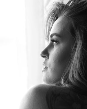 Black and white side profile portrait of a woman with a nose ring gazing toward a bright window.