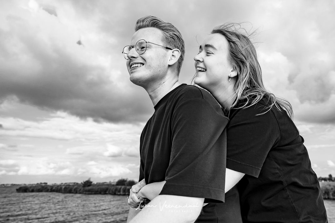 Zwart-witfoto van familieshoot op het Uitgeestermeer, zoon zit vooraan op de boot met zijn vriendin achter hem, zij kijkt over zijn schouder