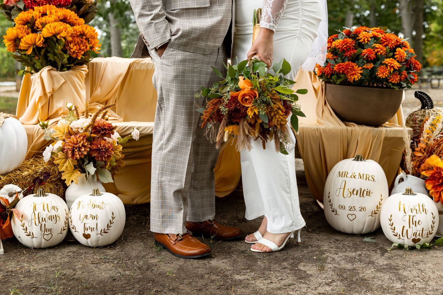 A couple embraces lovingly on a dirt path beside tall ornamental grasses on an overcast afternoon.