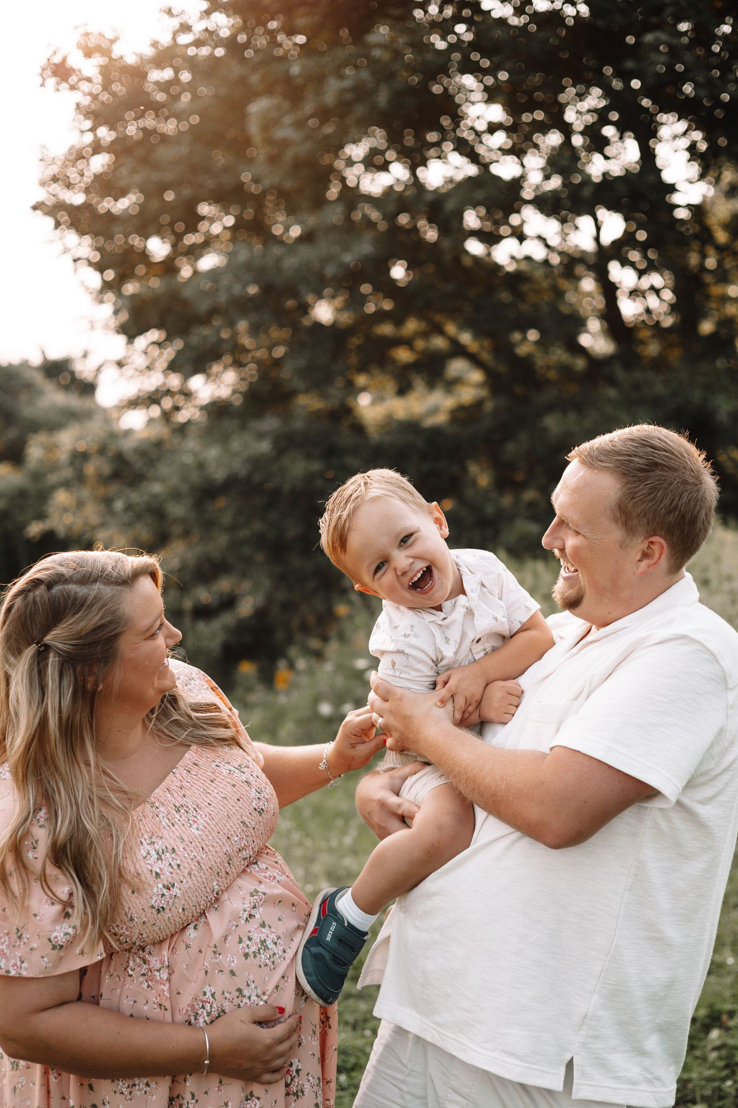 Candid moment of parents having fun with their toddler during a golden hour outdoor photo session
