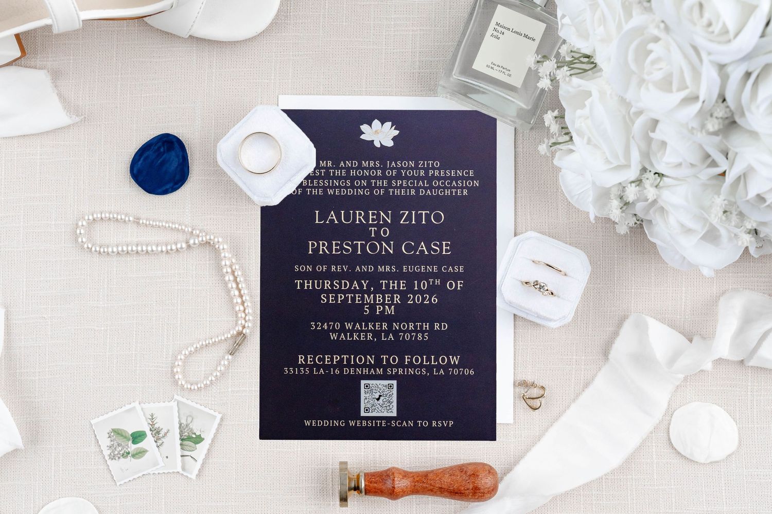 Navy blue wedding invitation suite for Lauren Zito and Preston Case, September 2024, displayed with pearl jewelry and white florals.