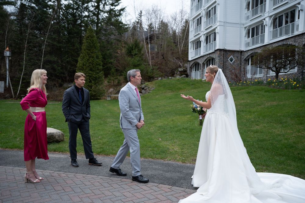 Bride in white gown meeting guests outside a hotel during outdoor wedding celebration.