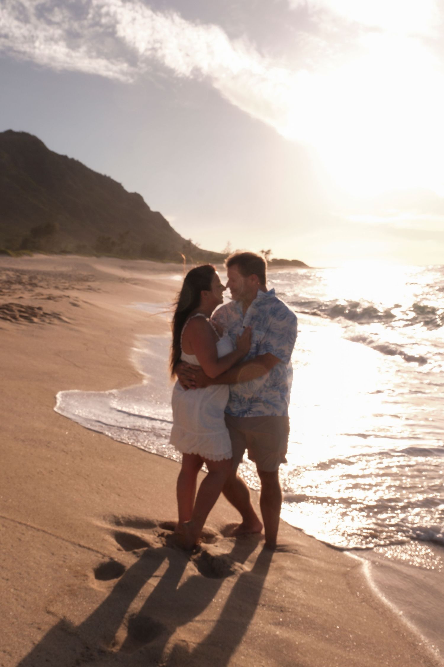 Couple embracing beside the ocean during a romantic North Shore Oahu sunset session