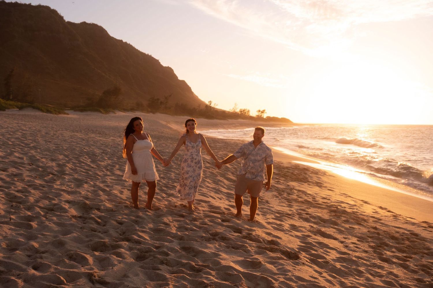 Family walking barefoot along a secluded North Shore Oahu beach during golden hour