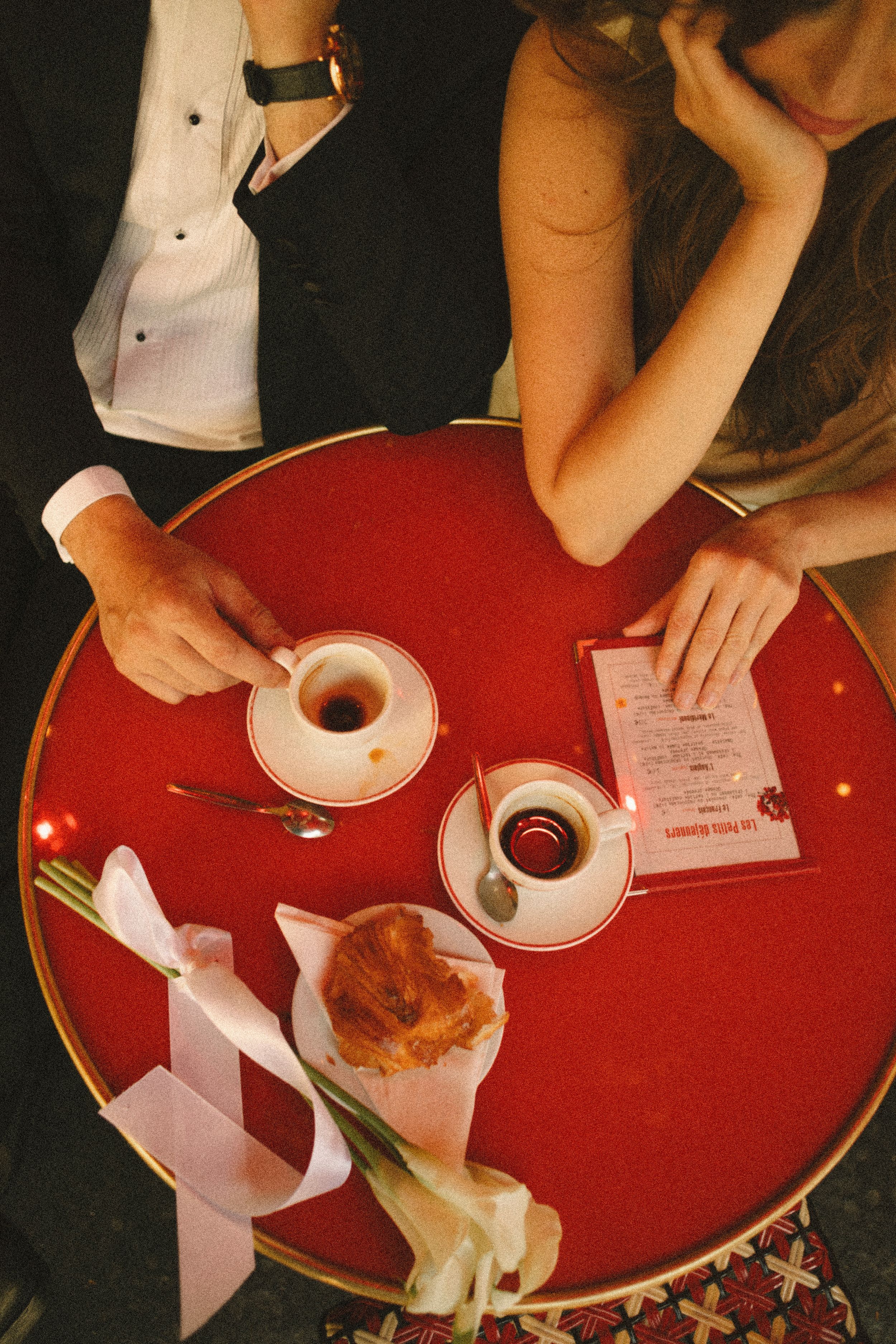 Bride and groom enjoying coffee and croissants at a Parisian café during their intimate destination wedding in Paris, France