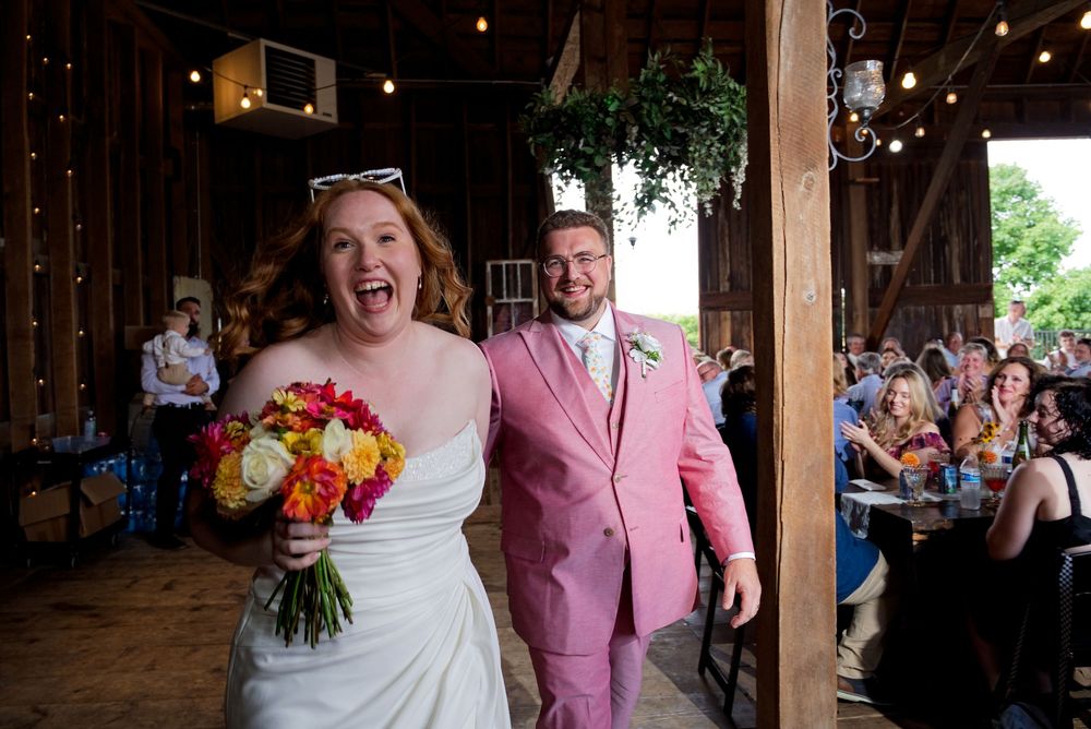 Bride and groom enter their reception space with high energy at The Centennial Barn in Wayland, MI