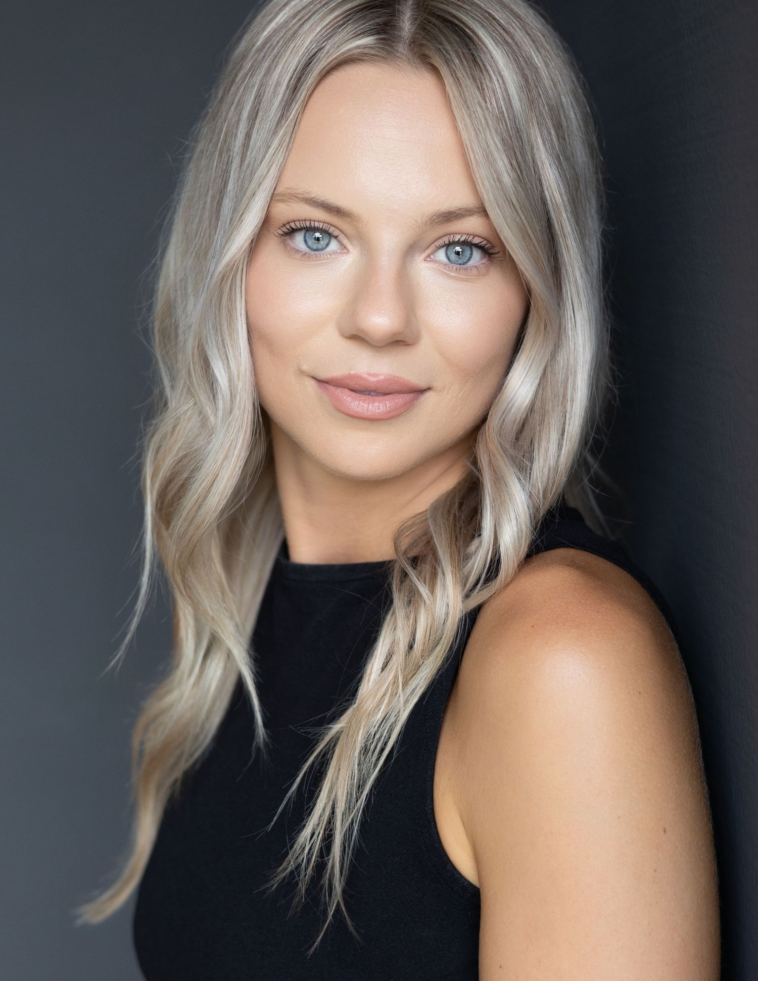 Model portfolio headshot with natural expression on dark grey backdrop