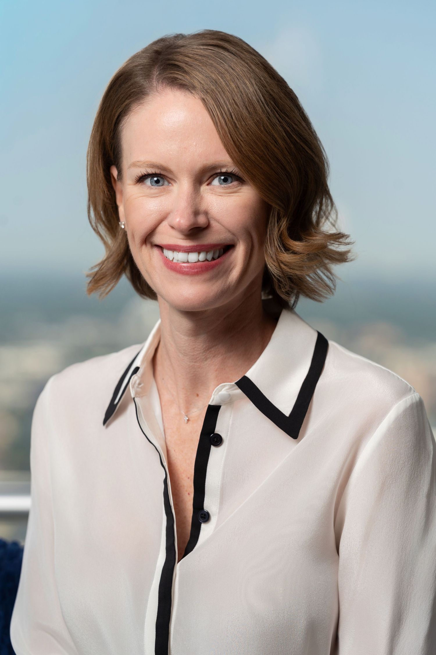 Smiling woman with long brown hair wearing a white coat in a professional headshot photo.