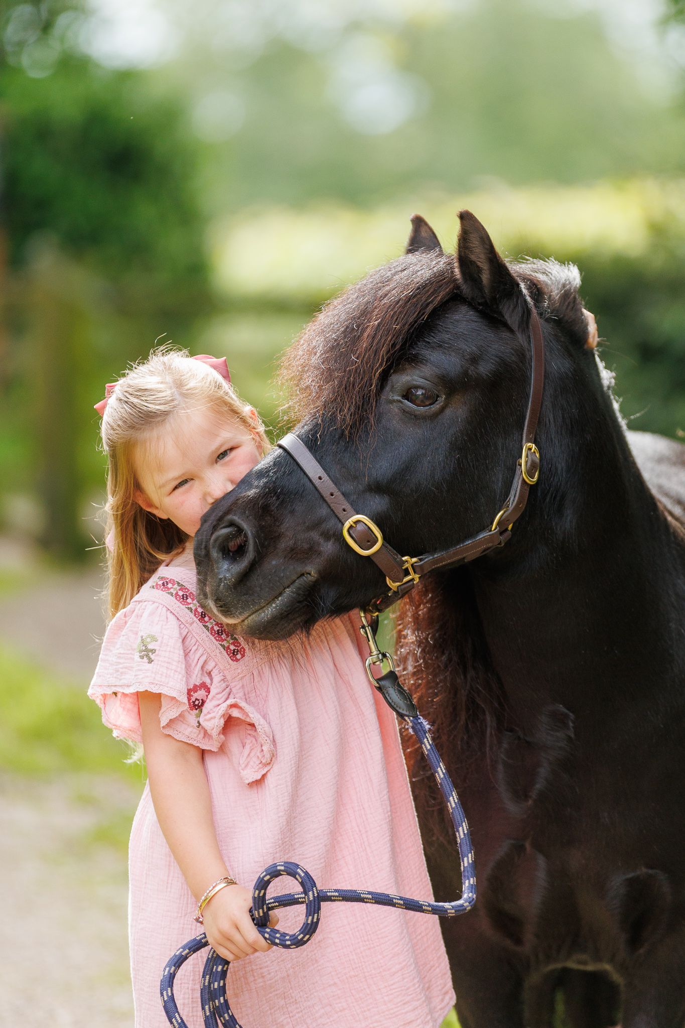 A smiling couple stands with a black and white horse and small dog in front of a white van on a farm.
