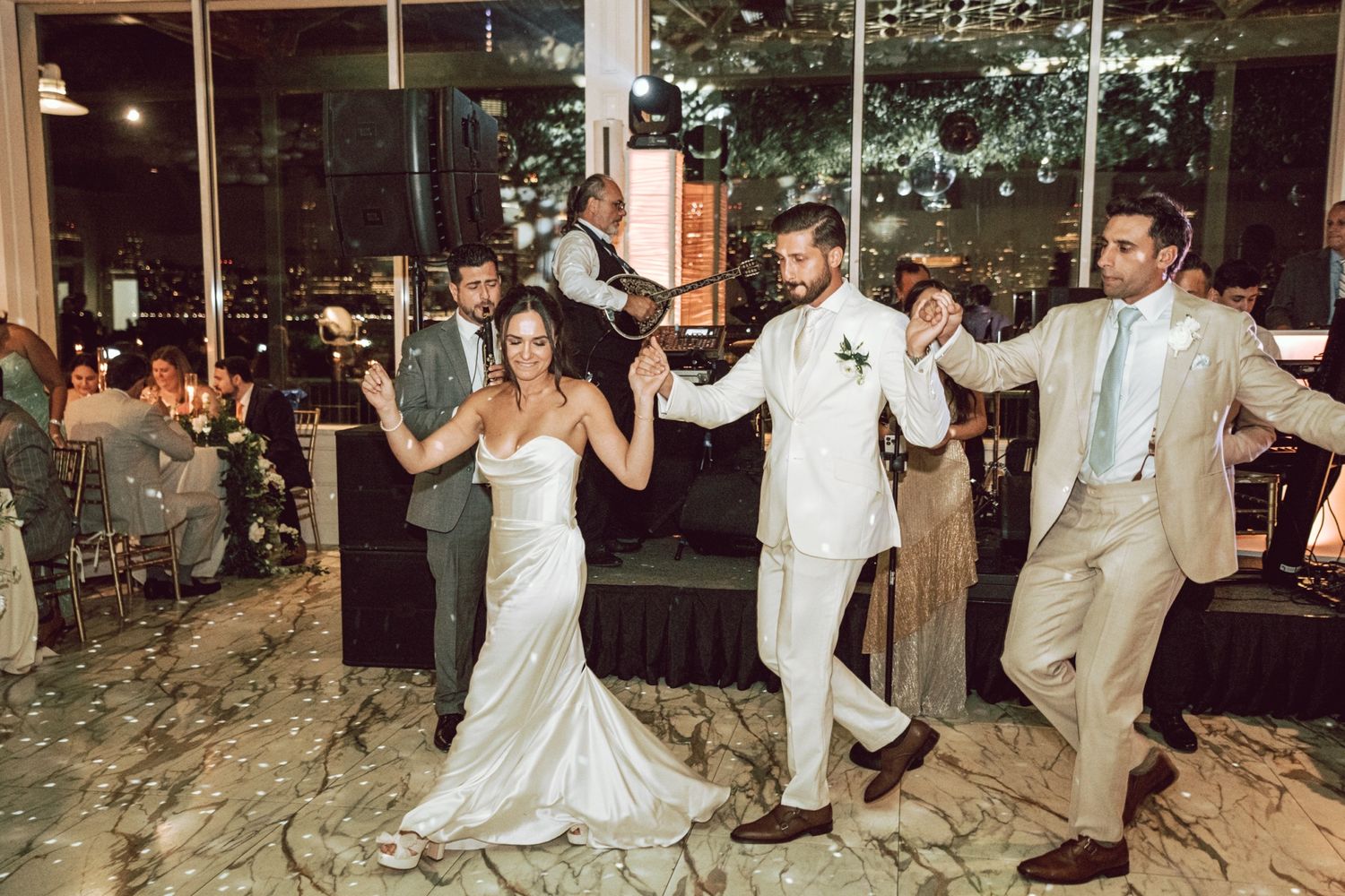 A bride and groom dance joyfully with guests at their wedding reception.