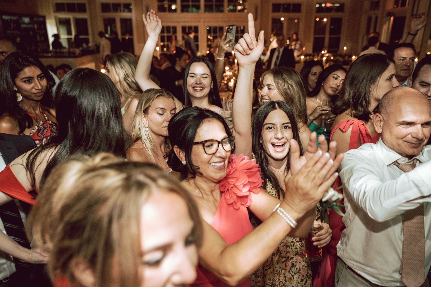 Guests dancing and celebrating joyfully at a wedding reception indoors.