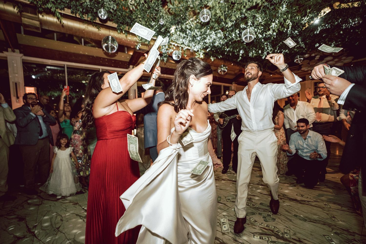 Bride dances joyfully with guests at lively outdoor wedding reception celebration.