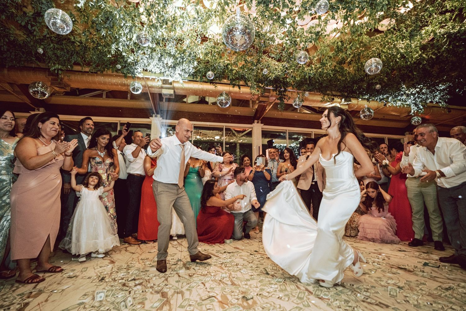 Bride and groom dancing joyfully surrounded by cheering guests at a festive wedding reception.