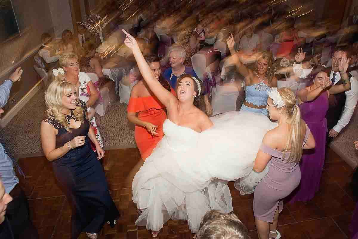 Bride in white gown dances with guests while dancing at the wedding reception at North Lakes Hotel & Spa at Penrith