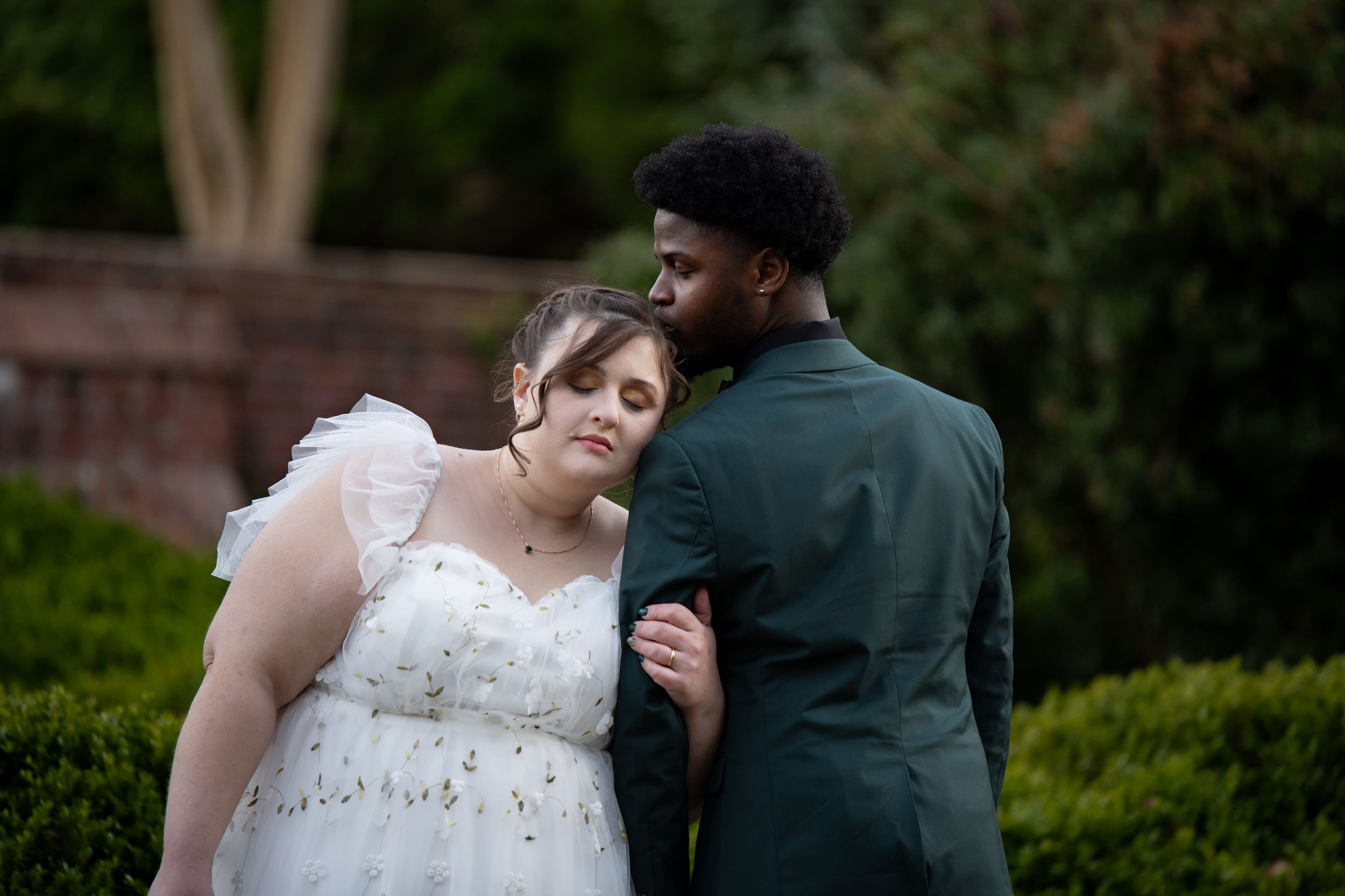 A tender moment between newlyweds in a garden setting as they embrace during their wedding photoshoot.