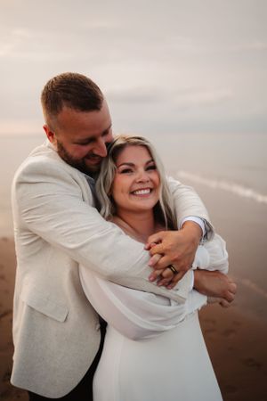 A joyful embrace captured during a beach photoshoot at dusk.