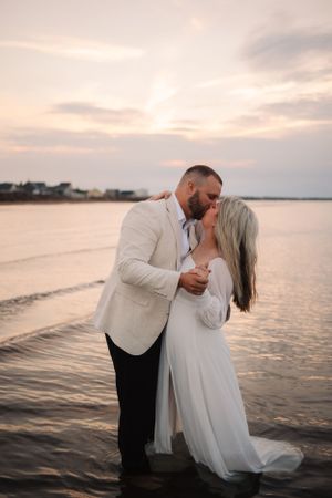 A romantic dip pose captured during a sunset beach photography session.