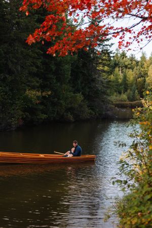 A wooden canoe glides across a lake surrounded by vibrant fall foliage.