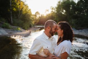 Intimate moment shared between couple by rushing waterfall at sunset.