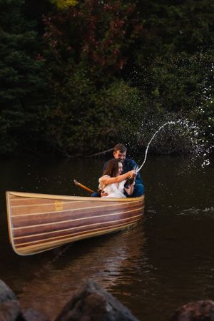 Romantic couple sharing intimate moment in wooden canoe on tranquil lake during sunset.