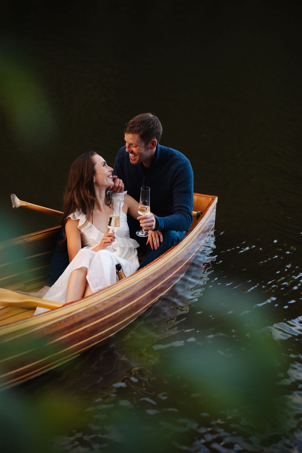 Romantic scene of couple in wooden boat with water splashing around them.