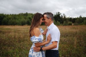 A couple embraces in a golden field during a romantic outdoor photoshoot.