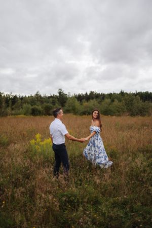 A couple dances together in a wildflower meadow on a cloudy day.